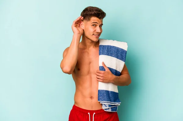 Young Caucasian Man Holding Beach Towel Isolated Blue Background Trying — Stock Photo, Image