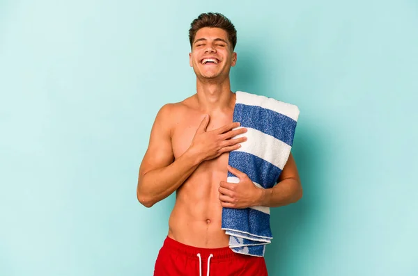Young Caucasian Man Holding Beach Towel Isolated Blue Background Laughs — Stockfoto