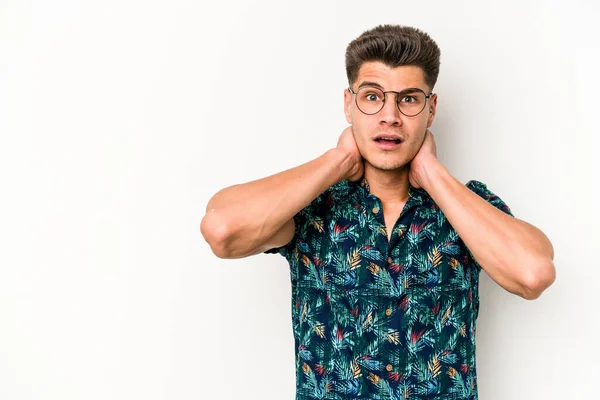 Beyaz arka planda izole edilmiş genç beyaz bir adam kafasının arkasına dokunuyor, düşünüyor ve bir seçim yapıyor..