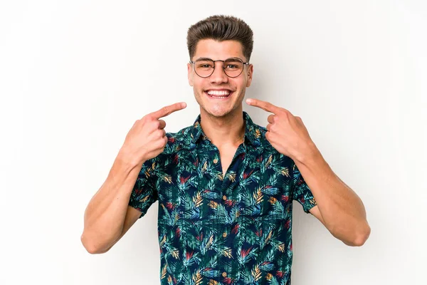 Beyaz arka planda izole edilmiş genç beyaz adam gülümsüyor, parmaklarını ağıza doğrultuyor..