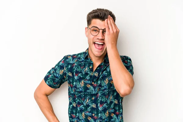 Beyaz arka planda izole edilmiş genç beyaz bir adam yüzünün yarısını palmiye ile örterek eğleniyor..