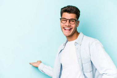 Mavi arka planda izole edilmiş beyaz bir genç hoş bir yüz ifadesi sergiliyor..