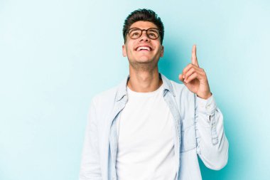 Mavi arka planda izole genç beyaz adam işaret iki ön parmakları boş bir boşluk gösteren.