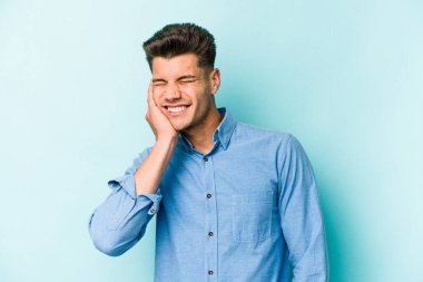 Genç beyaz adam mavi arka planda izole edilmiş parmaklarıyla kulaklarını kapatıyor, gürültülü bir ortam tarafından stresli ve umutsuz..