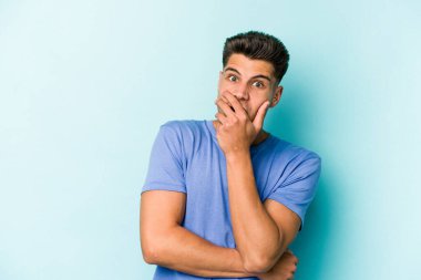 Kafkasyalı genç adam mavi arka planda izole edilmiş korkmuş ve korkmuş..