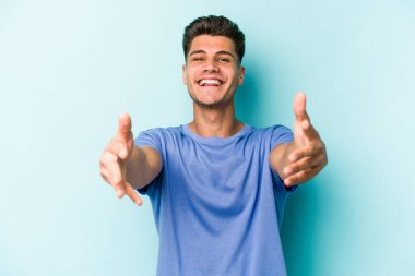 Mavi arka planda izole edilmiş beyaz bir genç hoş bir yüz ifadesi sergiliyor..