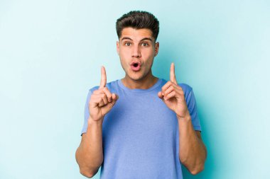 Mavi arka planda izole edilmiş beyaz bir adam ağzı açık bir şekilde üst tarafı işaret ediyor..