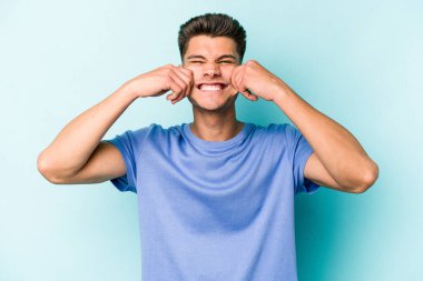 Kafkasyalı genç adam mavi arka planda izole edilmiş iki seçenek arasında şüphe duyuyor.