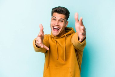 Mavi arka planda izole edilmiş genç beyaz adam kameraya sarıldığı için kendinden emin hissediyor..