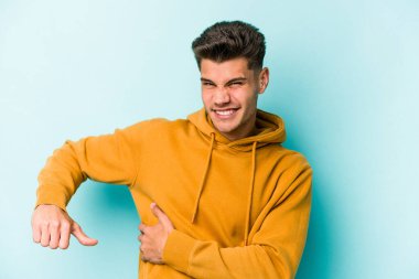 Mavi arka planda karaciğer ağrısı çeken, karnı ağrıyan genç beyaz bir adam..