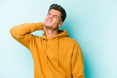 Kafkasyalı genç adam mavi arka planda izole edilmiş dirsek masajı yapıyor, kötü bir hareketin ardından acı çekiyor..