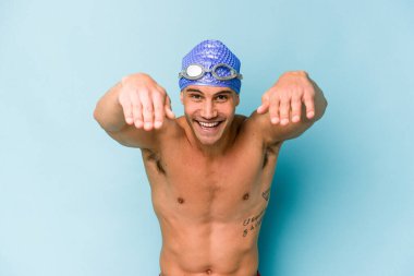 Genç beyaz yüzücü mavi arka planda izole edilmiş.