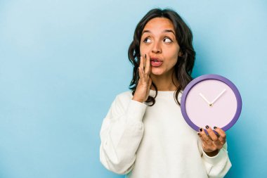 Mavi arka planda izole bir saat tutan genç İspanyol kadın gizli bir sıcak fren haberi söylüyor ve yana bakıyor