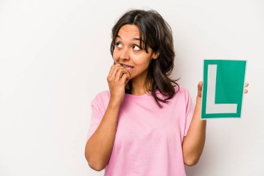 Genç İspanyol kadın elinde acemi sürücü tabelası tutuyordu. Beyaz arka planda izole edilmişti. Bir şeyin fotokopi odasına baktığını sanıyordu..