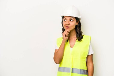 Beyaz arka planda izole edilmiş genç bir işçi kadın şüpheli ve şüpheci bir ifadeyle yana bakıyor..