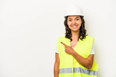 Young laborer hispanic woman isolated on white background smiling and pointing aside, showing something at blank space.