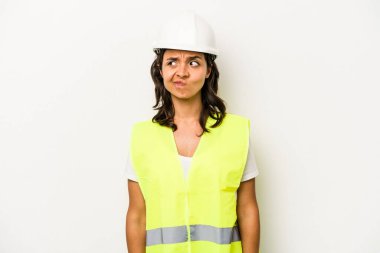 Latin kökenli genç bir kadın beyaz arka planda izole edilmiş. Kafası karışmış, şüpheli ve kendinden emin değil..