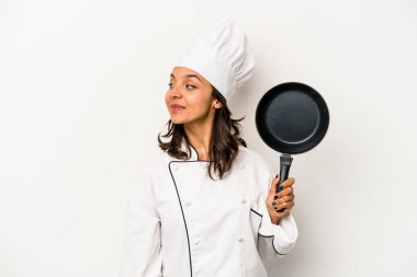 Beyaz arka planda soyutlanmış genç İspanyol aşçı kadın gülümsüyor, neşeli ve keyifli görünüyor..