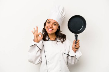 Genç İspanyol aşçı kadın, beyaz arka planda izole edilmiş neşeli ve kendinden emin, iyi bir jest yapıyor..