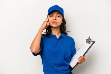 Genç İspanyol kadın teslimatçı beyaz arka planda izole edilmiş, parmağıyla tapınağı işaret eden, düşünen, bir göreve odaklanmış..