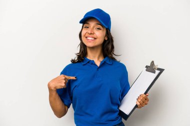 Beyaz arka planda izole edilmiş genç İspanyol kadın teslimatçı elle bir fotokopi alanını işaret ediyor, gururlu ve kendinden emin.