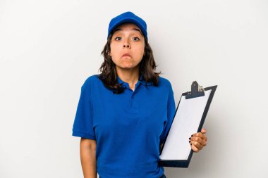 Beyaz arka planda izole edilmiş genç İspanyol kadın teslimatçı omuzlarını silker ve gözleri açık kalır..