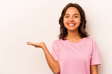 Beyaz arka planda izole edilmiş genç İspanyol kadın, avuç içi fotokopi alanı tutmaktan etkilenmiş..