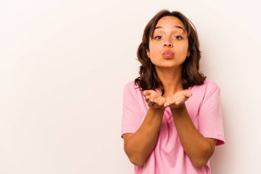 Beyaz arka planda izole edilmiş, dudakları kıvrılmış ve hava öpücüğü yollamak için avuç içi tutan genç İspanyol kadın..