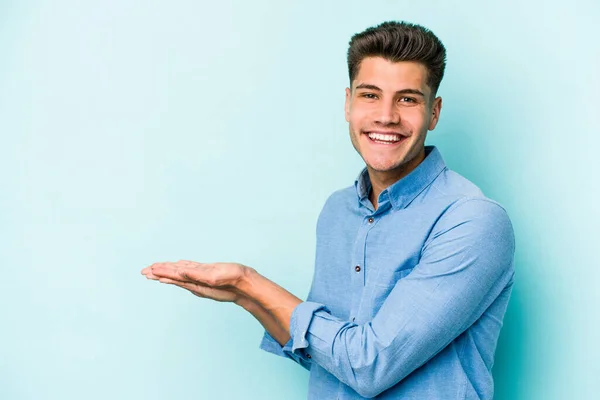 Joven Hombre Caucásico Aislado Sobre Fondo Azul Sosteniendo Espacio Copia —  Fotos de Stock