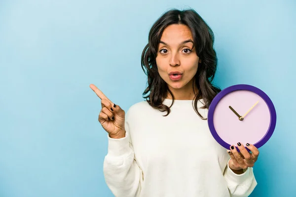 Mujer Hispana Joven Sosteniendo Reloj Aislado Sobre Fondo Azul Apuntando — Foto de Stock