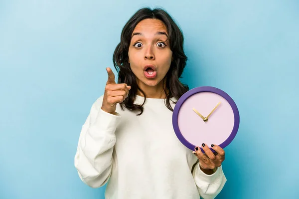 Νεαρή Ισπανίδα Που Κρατάει Ένα Ρολόι Απομονωμένο Μπλε Φόντο Έχοντας — Φωτογραφία Αρχείου