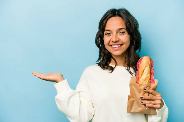 Young Hispanic Woman Eating Sandwich Isolates Blue Background Showing Copy — Stockfoto