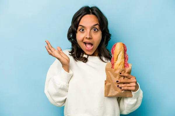 Young Hispanic Woman Eating Sandwich Isolates Blue Background Surprised Shocked — Stockfoto