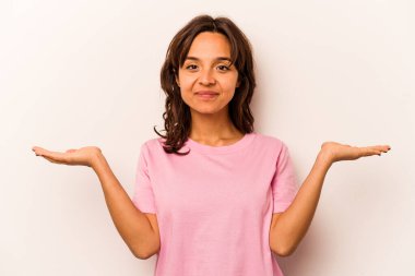 Beyaz arka planda izole edilmiş genç İspanyol kadın kollarıyla ölçeği yapıyor, mutlu ve kendinden emin hissediyor..