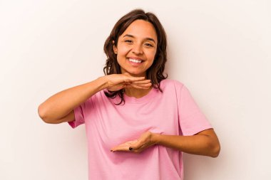 Beyaz arka planda izole edilmiş genç İspanyol kadın iki eliyle bir şey tutuyor, ürün sunumu..