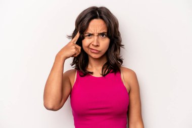 Beyaz arka planda izole edilmiş genç İspanyol bir kadın şakağı parmağıyla işaret ediyor, düşünüyor ve bir göreve odaklanıyor..