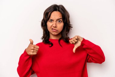 Latin kökenli genç bir kadın beyaz arka planda izole edilmiş, baş parmağını kaldırıyor, zor seçim konsepti.