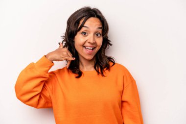 Beyaz arka planda izole edilmiş genç İspanyol kadın parmaklarıyla bir cep telefonu hareketi gösteriyor..