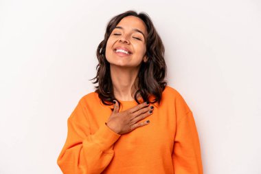 Beyaz arka planda izole edilmiş genç İspanyol kadın yüksek sesle gülüyor elini göğsüne koyuyor..