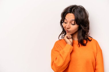 Beyaz arka planda izole edilmiş genç İspanyol kadın şüpheli ve şüpheci bir ifadeyle yana bakıyor..