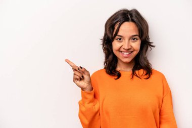 Beyaz arka planda izole edilmiş genç İspanyol kadın işaret parmağıyla işaret ederek gülümsüyor..