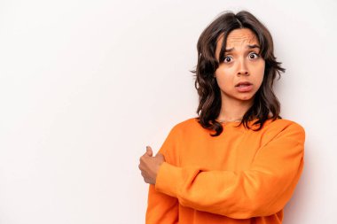 Beyaz arka planda izole edilmiş genç İspanyol kadın gülümsüyor ve boş alanda bir şeyler gösteriyor..