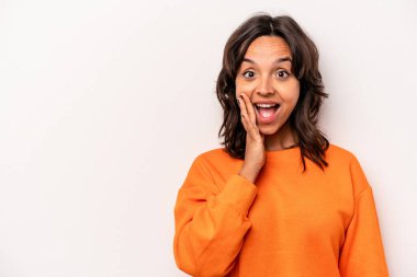 Beyaz arka planda izole edilmiş genç İspanyol kadın yüksek sesle bağırıyor, gözleri açık ve elleri gergin tutuyor..