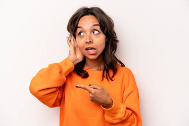 Beyaz arka planda izole edilmiş genç İspanyol kadın bir dedikoduyu dinlemeye çalışıyor..