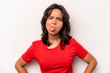 Beyaz arka planda izole edilmiş genç bir İspanyol kadın. Komik ve dost canlısı bir dil uzatıyor..