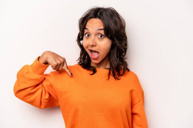 Beyaz arka planda izole edilmiş genç İspanyol kadın gömlek fotokopi alanını elle işaret ediyor, gururlu ve kendinden emin.