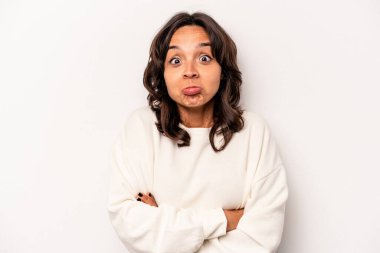 Beyaz arka planda izole edilmiş genç İspanyol kadın omuz silkiyor ve gözleri açık..