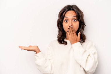 Beyaz arka planda izole edilmiş genç İspanyol kadın, avuç içi fotokopi alanı tutmaktan etkilenmiş..