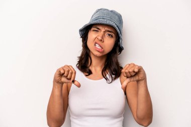 Beyaz arka planda izole edilmiş genç İspanyol kadın baş parmağını aşağı gösteriyor ve hoşlanmadığını ifade ediyor..