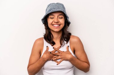 Beyaz arka planda izole edilmiş genç İspanyol kadın yüksek sesle gülüyor elini göğsüne koyuyor..